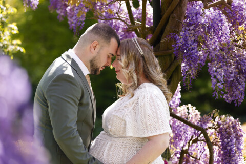 Foto van bruidspaar met paarse bloemen op de achtergrond
